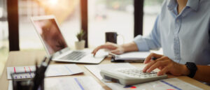 Business owner at a desk calculating the tax impact of how to pay yourself as an LLC.
